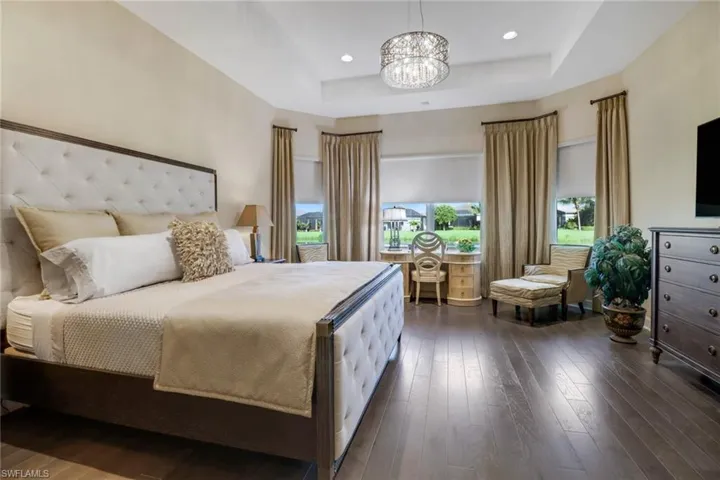Bedroom featuring dark hardwood flooring, a chandelier, and a tray ceiling