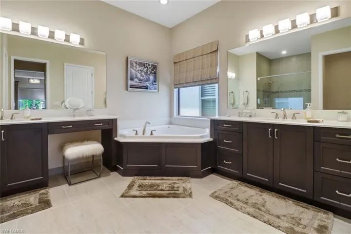Bathroom with dual vanity, a tub to relax in, and tile patterned flooring