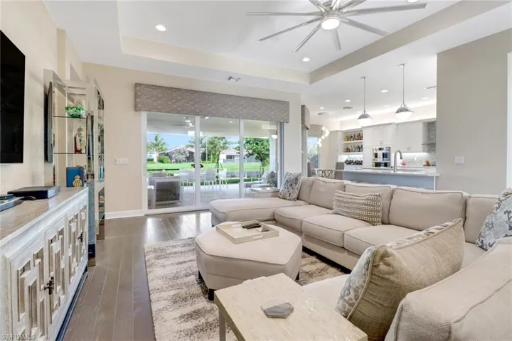 Living room with hardwood flooring, sink, ceiling fan, and a tray ceiling