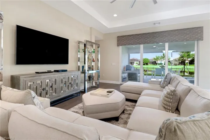 Living room with a tray ceiling, ceiling fan, and hardwood flooring