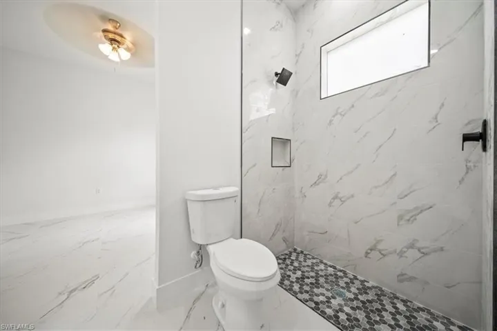 Bathroom with a marble finish shower and marble finish floors