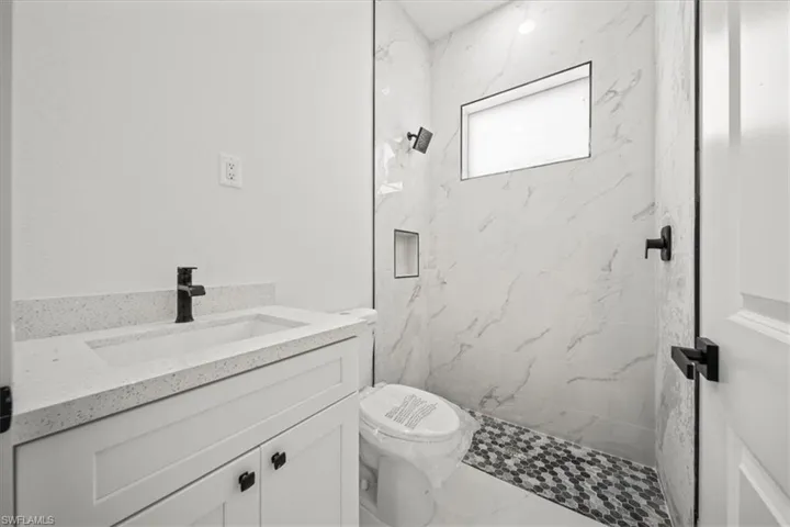 Bathroom with a marble finish shower, vanity, and marble finish flooring
