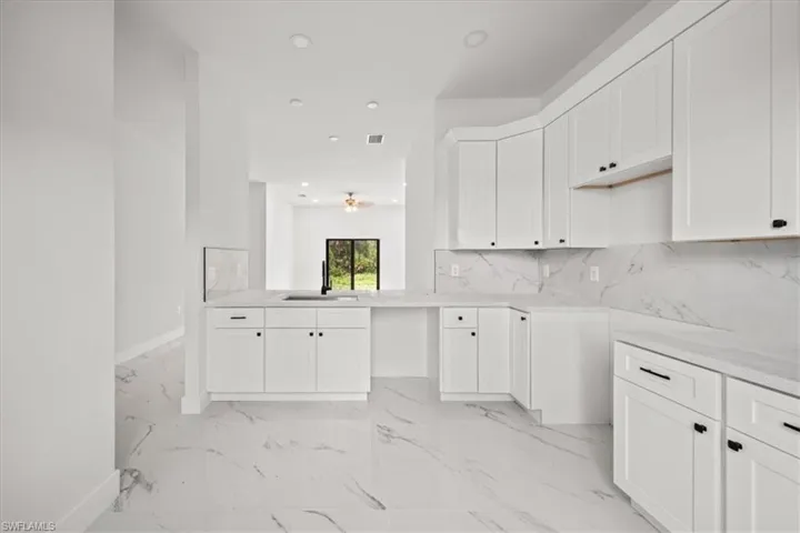 Kitchen with light marble finish flooring, recessed lighting, tasteful backsplash, white cabinetry, and light countertops