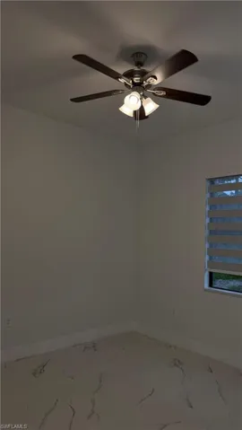 Empty room featuring ceiling fan and marble look tile flooring