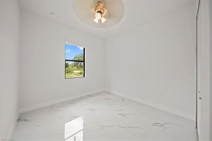 Spare room featuring marble finish floors and a ceiling fan