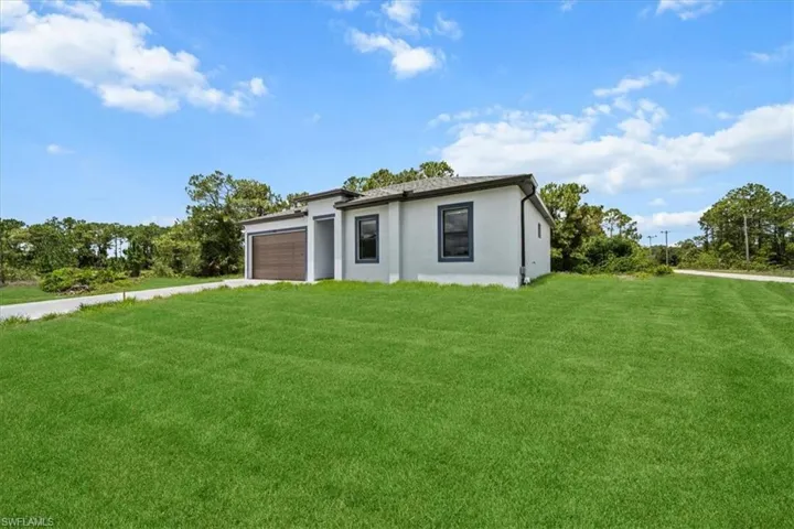 View of front of house featuring an attached garage, driveway, a front yard, and stucco siding