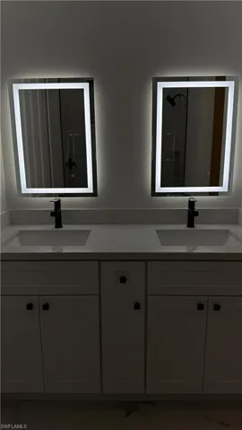 Full bathroom featuring double vanity and marble look tiles