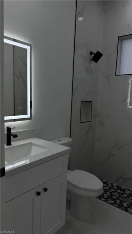 Bathroom featuring vanity, a marble finish shower, marble finish floors, and a textured wall
