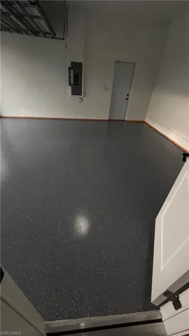 Garage featuring electric panel and baseboards