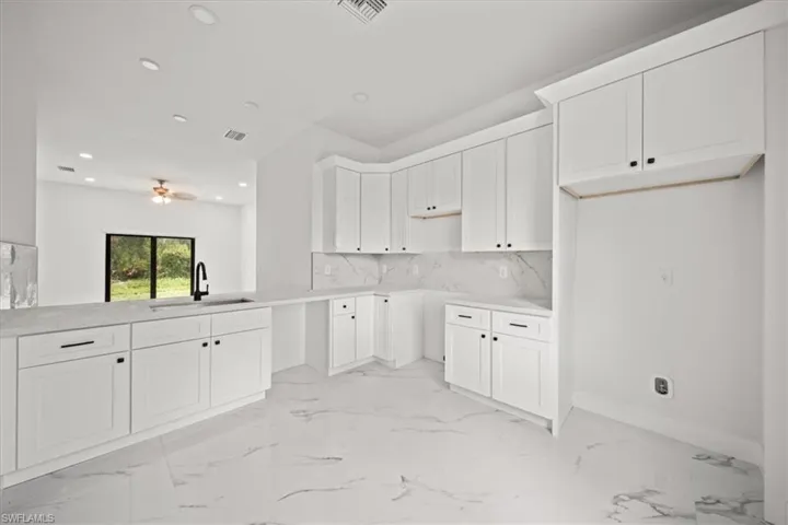 Kitchen with recessed lighting, ceiling fan, decorative backsplash, white cabinets, and light marble finish flooring