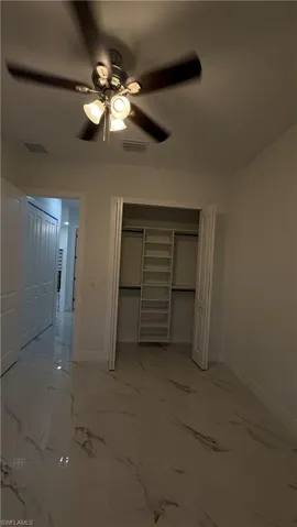 Unfurnished bedroom featuring a closet, ceiling fan, and light marble finish flooring