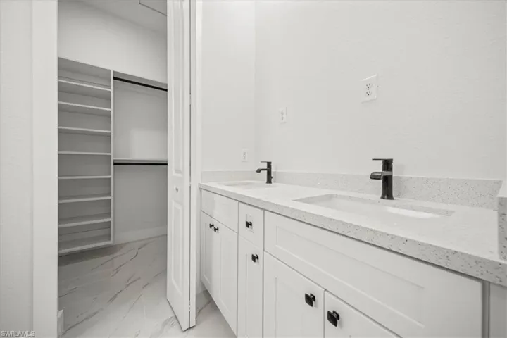 Full bath with marble finish floors and double vanity
