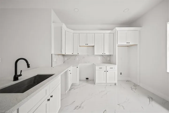 Kitchen with light marble finish flooring, white cabinets, and decorative backsplash