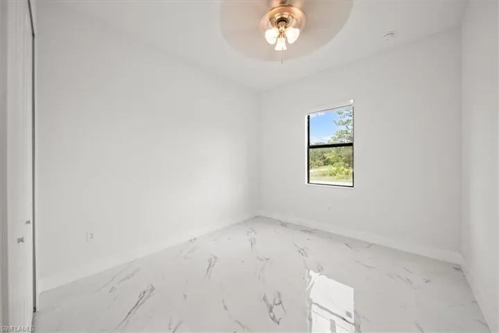 Spare room featuring light marble finish floors and ceiling fan