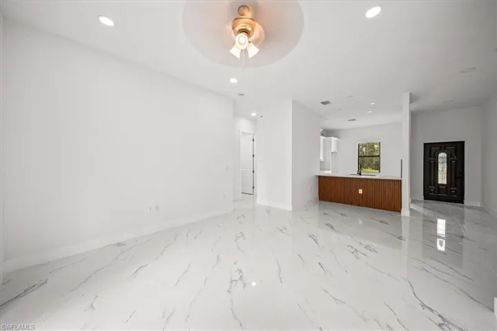 Unfurnished living room featuring ceiling fan, recessed lighting, and light marble finish flooring