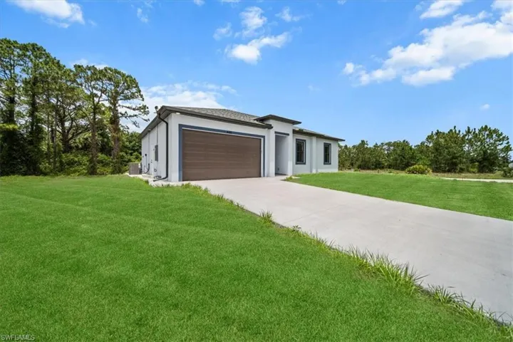 Contemporary home featuring a front yard, a garage, concrete driveway, and stucco siding