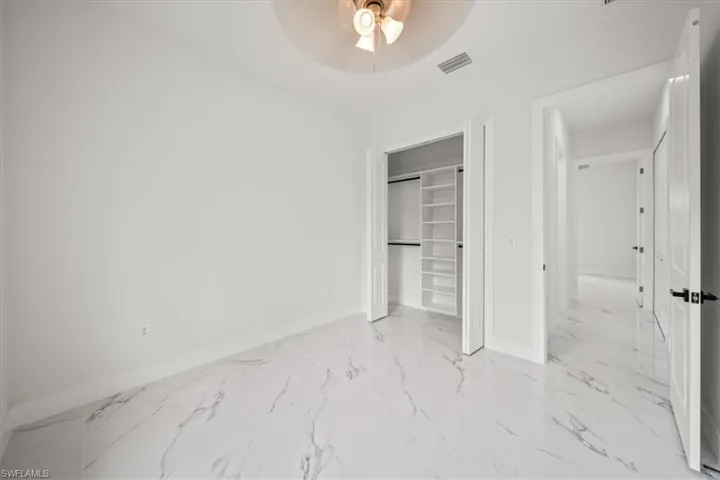 Unfurnished bedroom with marble finish flooring, a closet, and a ceiling fan