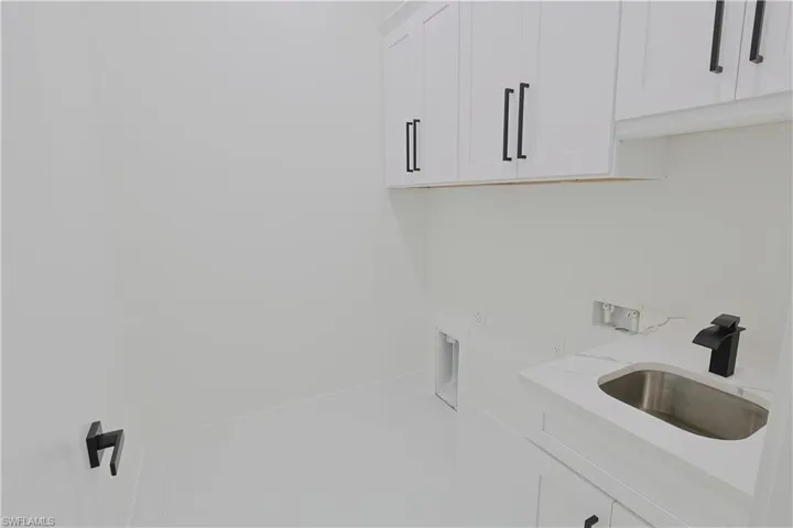 Washroom with baseboards, tile patterned floors, washer hookup, cabinet space, and a sink