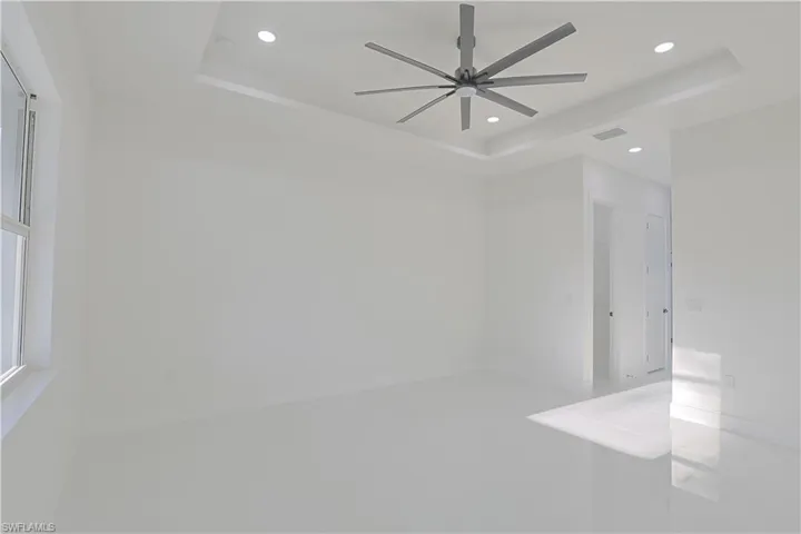 Empty room featuring recessed lighting, visible vents, a tray ceiling, and ceiling fan