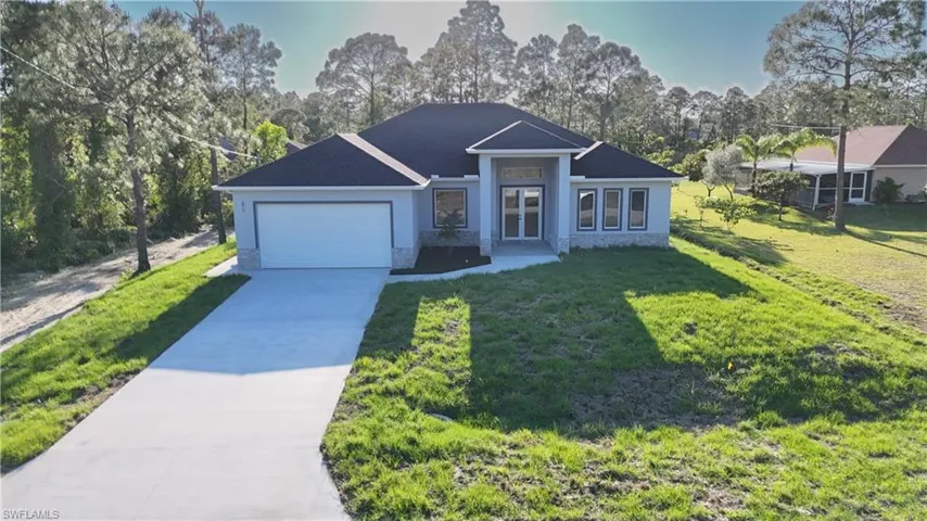 View of front facade featuring driveway, a front lawn, stucco siding, and an attached garage