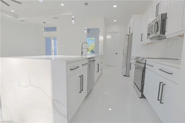 Kitchen featuring recessed lighting, white cabinets, appliances with stainless steel finishes, pendant lighting, and a sink