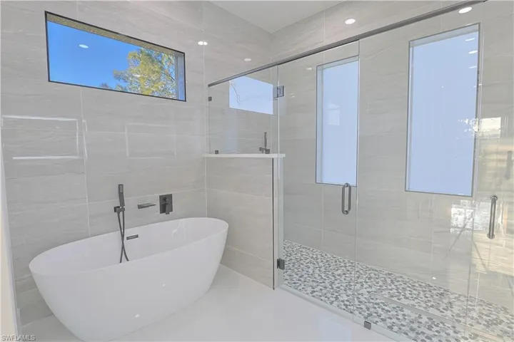 Full bathroom featuring tile walls, a freestanding tub, and a stall shower