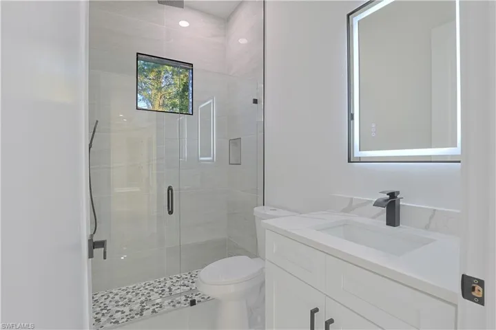 Full bath featuring toilet, a stall shower, and vanity