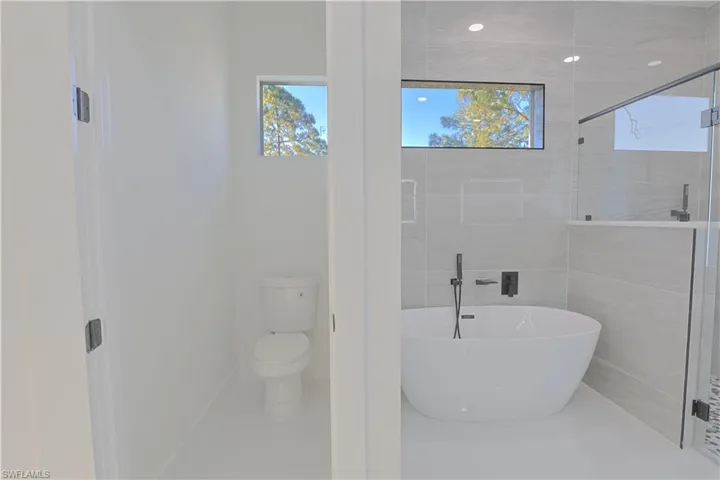 Full bath featuring a freestanding bath, toilet, and a stall shower