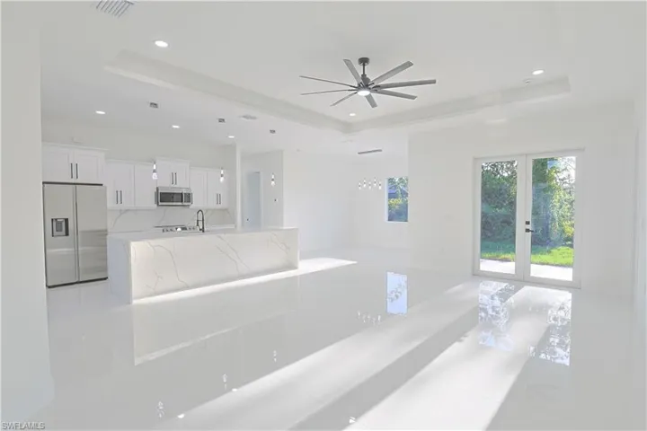 Unfurnished living room with a tray ceiling, ceiling fan, visible vents, and recessed lighting
