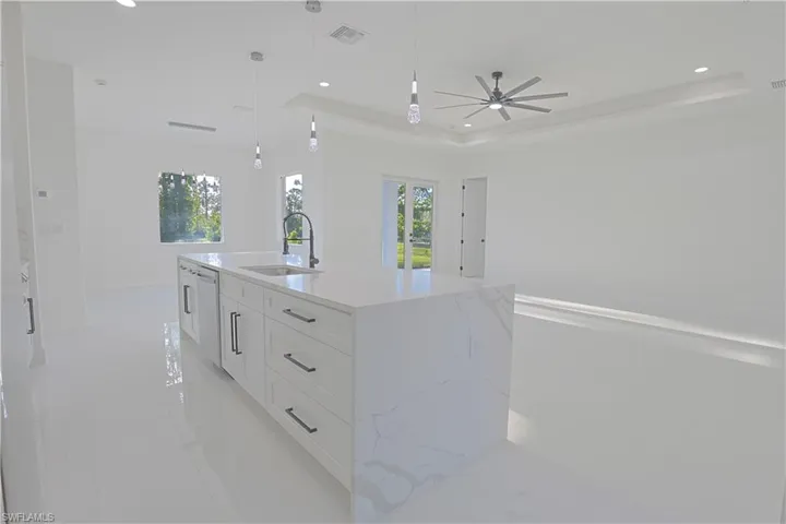 Kitchen featuring light tile patterned floors, a ceiling fan, white cabinets, visible vents, and a sink