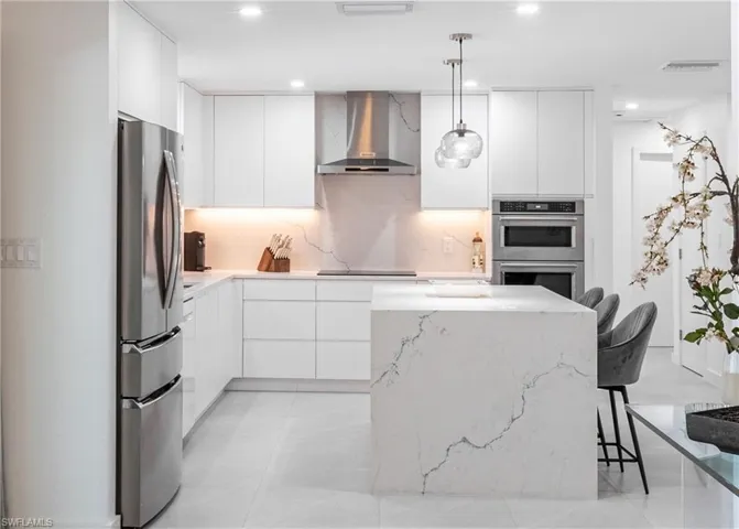Kitchen featuring wall chimney range hood, appliances with stainless steel finishes, modern cabinets, white cabinetry, and recessed lighting