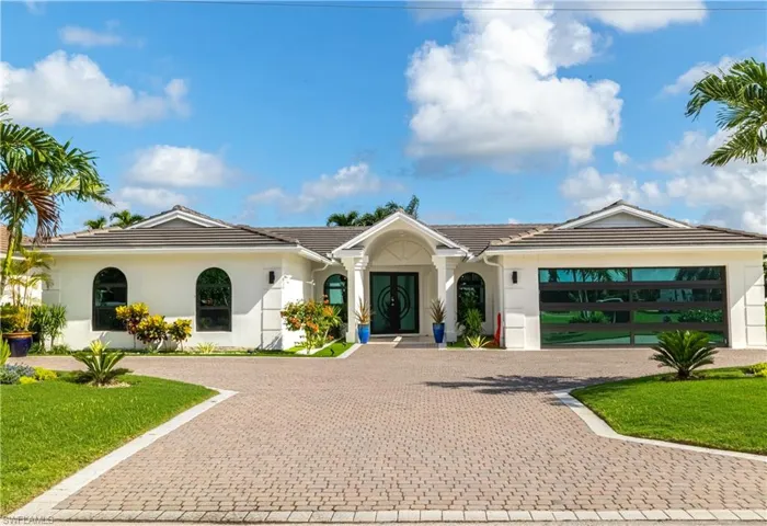 Ranch-style house with stucco siding, curved driveway, a tile roof, and a front lawn