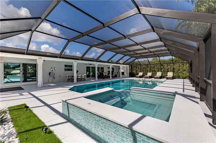 View of swimming pool featuring a patio, a ceiling fan, glass enclosure, and a pool with connected hot tub