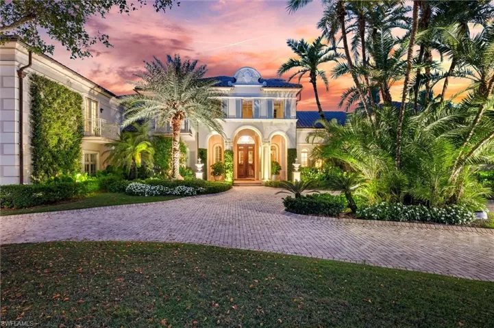 Mediterranean / spanish-style home with stucco siding, a balcony, curved driveway, and french doors