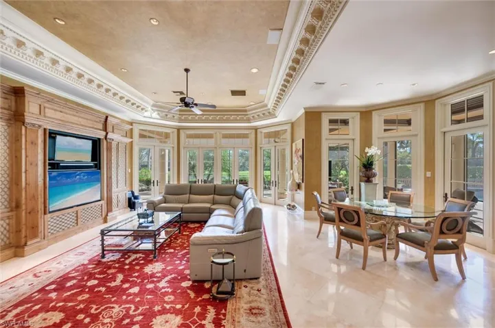 Living room with ornamental molding, a raised ceiling, and ceiling fan
