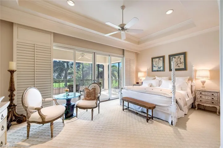 Bedroom featuring a tray ceiling, carpet, crown molding, access to exterior, and a ceiling fan