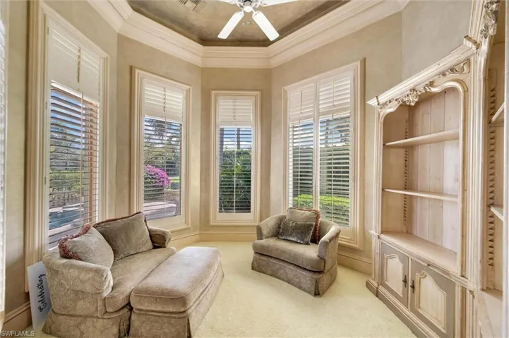 Living area with crown molding, a ceiling fan, and carpet