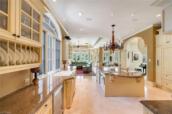 Kitchen with dark stone countertops, cream cabinets, ornamental molding, open floor plan, and a raised ceiling