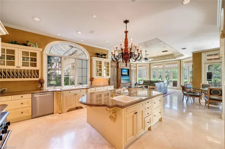 Kitchen with glass fronted cabinets, cream cabinets, crown molding, dark stone counters, and stainless steel appliances