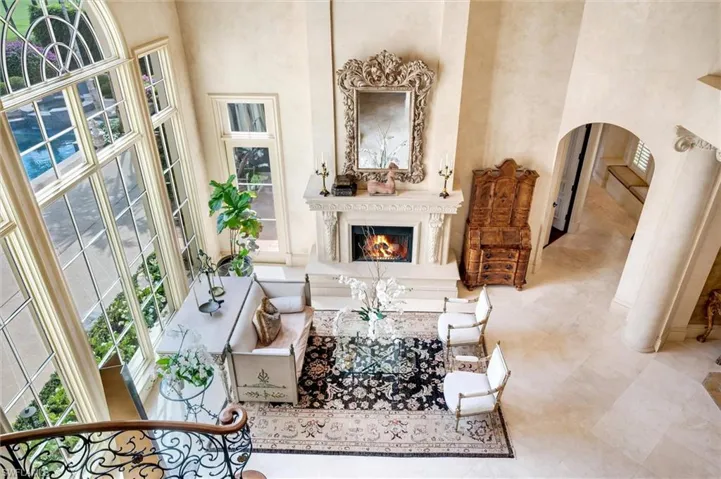 Living room featuring arched walkways, a lit fireplace, and a high ceiling