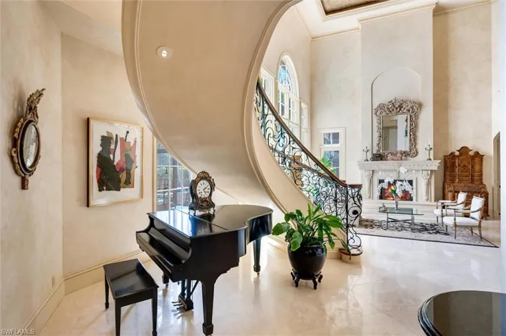 Living area featuring a high ceiling, a high end fireplace, arched walkways, and crown molding