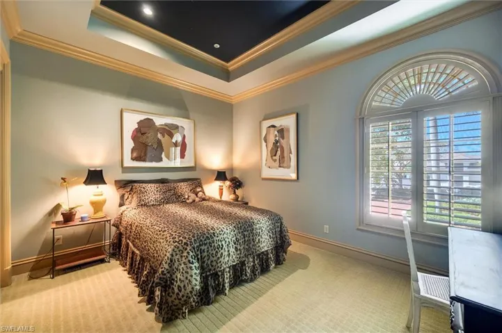 Bedroom featuring ornamental molding, light carpet, and a raised ceiling