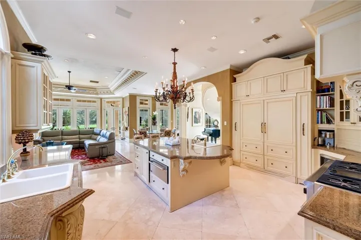 Kitchen featuring cream cabinetry, ornamental molding, open floor plan, dark stone countertops, and ceiling fan