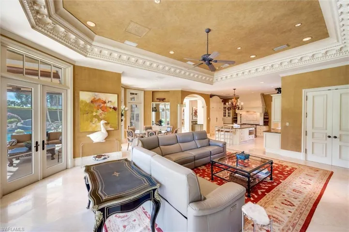 Living room featuring ornamental molding, a raised ceiling, ceiling fan, arched walkways, and hanging lights