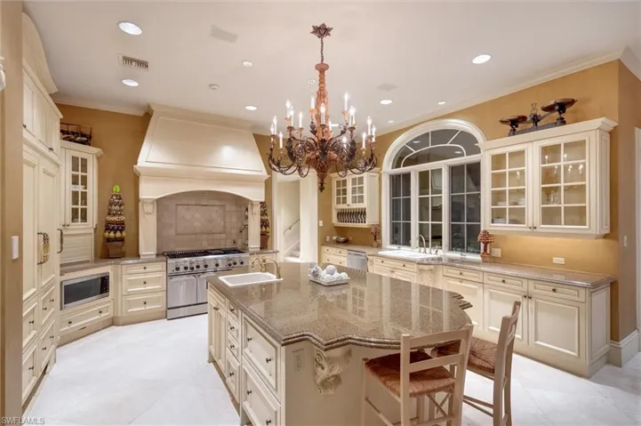 Kitchen featuring glass insert cabinets, a kitchen island with sink, dark stone counters, a breakfast bar area, and stainless steel appliances