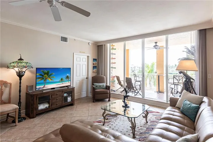 Tiled living area with a ceiling fan, floor to ceiling windows, and crown molding