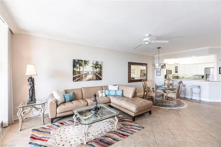 Living area with light tile patterned floors, crown molding, and a ceiling fan