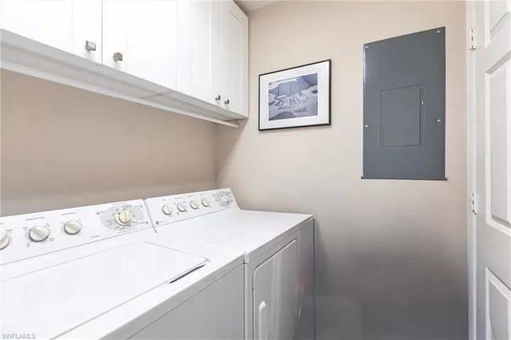 Laundry room with cabinet space, electric panel, and washing machine and dryer