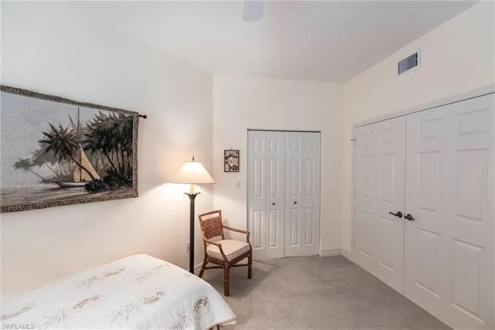 Bedroom featuring light colored carpet, ceiling fan, and multiple closets