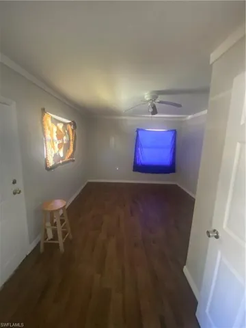 Spacious room with wood-finish flooring, light gray walls, and white crown molding
